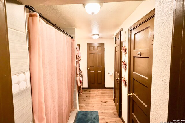 corridor featuring light hardwood / wood-style flooring and a textured ceiling