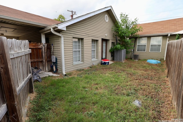 exterior space with central AC unit and a lawn