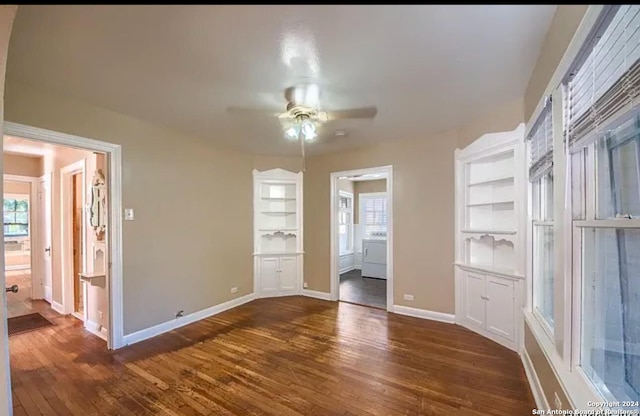 spare room featuring built in shelves, dark hardwood / wood-style flooring, and ceiling fan