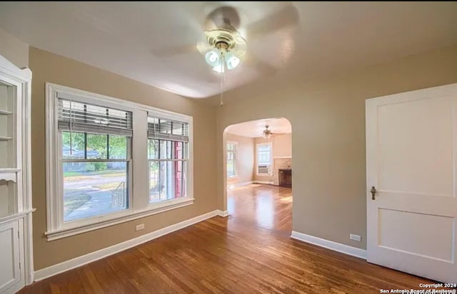 unfurnished room featuring ceiling fan, wood-type flooring, and a healthy amount of sunlight