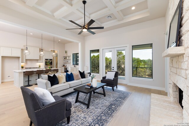 living room with coffered ceiling, a fireplace, beam ceiling, light wood-type flooring, and a high ceiling