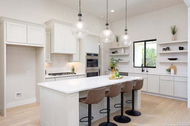 kitchen with stainless steel appliances, a center island, white cabinets, sink, and backsplash