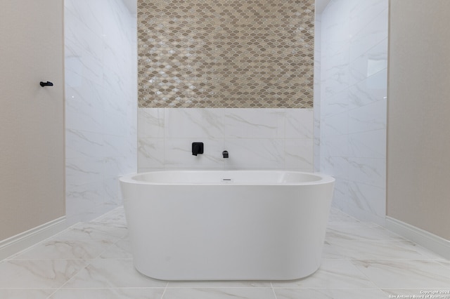 bathroom with a tub to relax in and tile walls