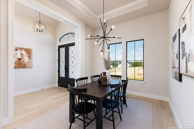 dining area featuring light wood-type flooring, french doors, and a notable chandelier