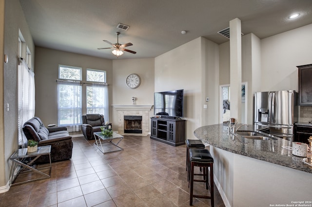 living room featuring sink, ceiling fan, a textured ceiling, tile patterned floors, and a tile fireplace