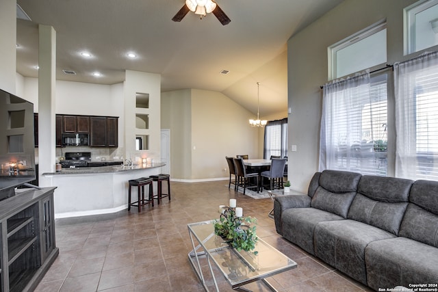 tiled living room featuring ceiling fan with notable chandelier and high vaulted ceiling