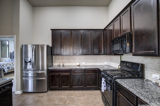 kitchen with dark brown cabinets, black appliances, dark stone counters, and backsplash