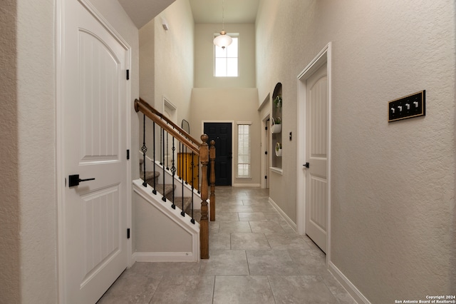 entryway with a towering ceiling and light tile patterned floors