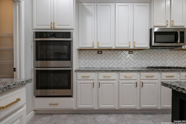 kitchen with stainless steel appliances, white cabinets, light stone counters, and tasteful backsplash