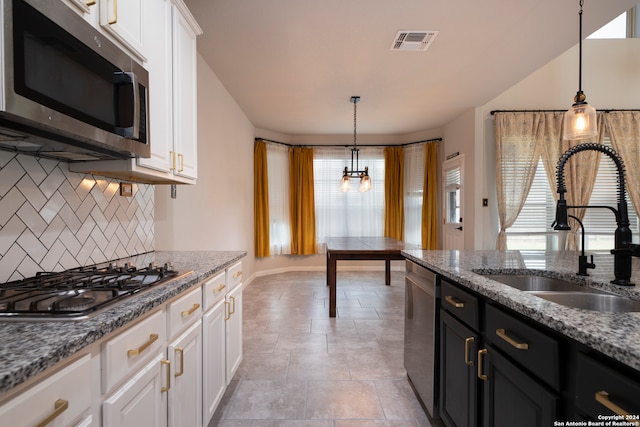 kitchen with white cabinetry, backsplash, appliances with stainless steel finishes, and decorative light fixtures