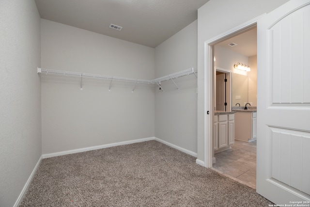 walk in closet with light colored carpet and sink