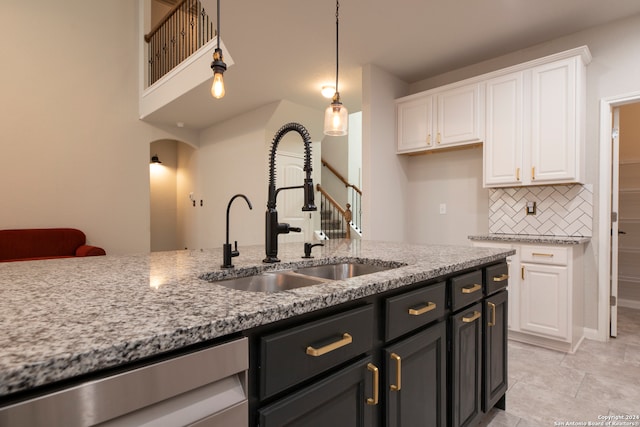 kitchen featuring light stone counters, sink, backsplash, white cabinetry, and decorative light fixtures