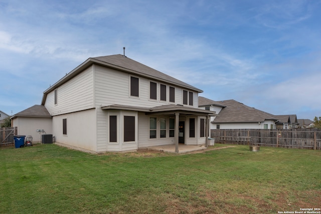 rear view of property with cooling unit, a yard, and a patio area