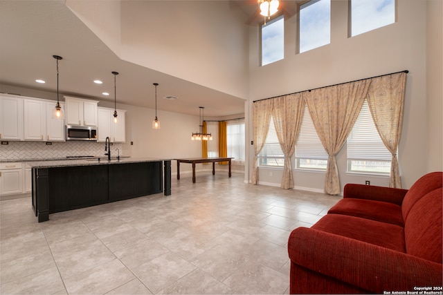 tiled living room featuring ceiling fan with notable chandelier and sink