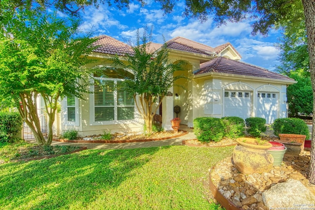 mediterranean / spanish-style home featuring a garage and a front yard