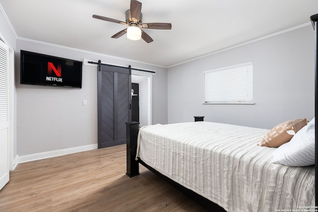 bedroom with crown molding, hardwood / wood-style floors, a barn door, and ceiling fan