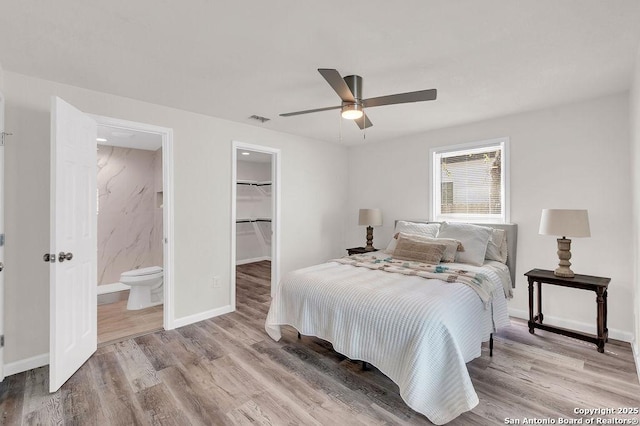 bedroom with a walk in closet, ensuite bath, ceiling fan, light hardwood / wood-style flooring, and a closet