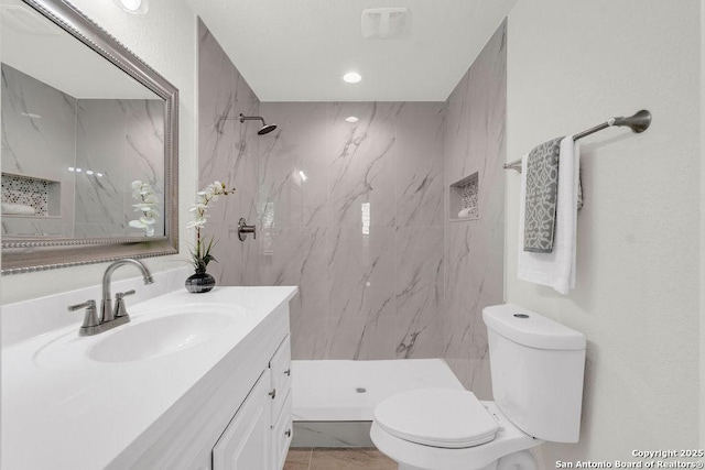 bathroom with vanity, toilet, and a tile shower