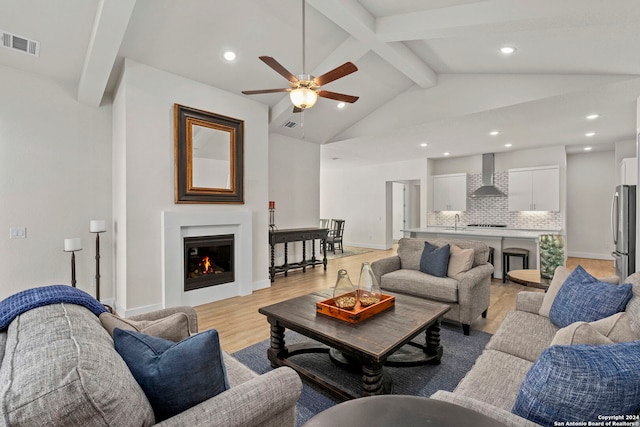 living room with lofted ceiling with beams, ceiling fan, sink, and light hardwood / wood-style floors