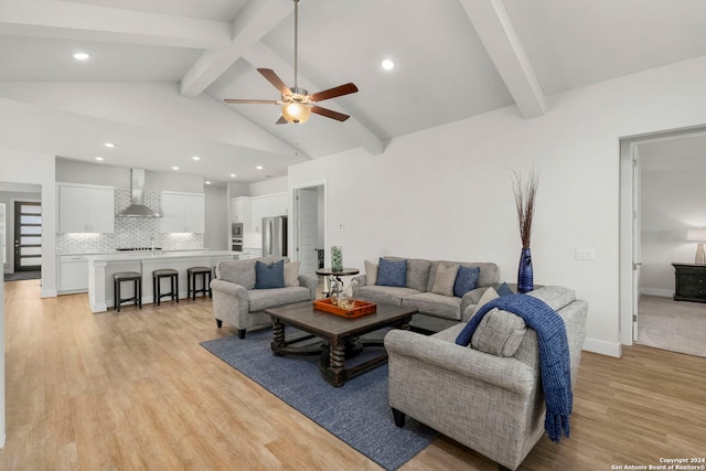 living room with ceiling fan, sink, light hardwood / wood-style flooring, and lofted ceiling with beams