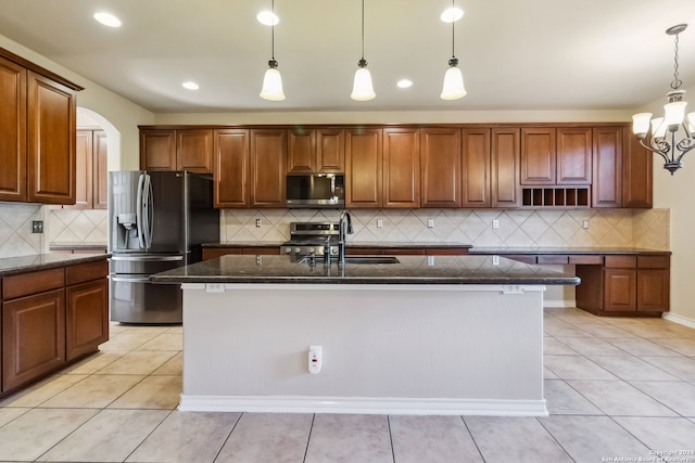 kitchen with a kitchen island with sink, decorative backsplash, and appliances with stainless steel finishes