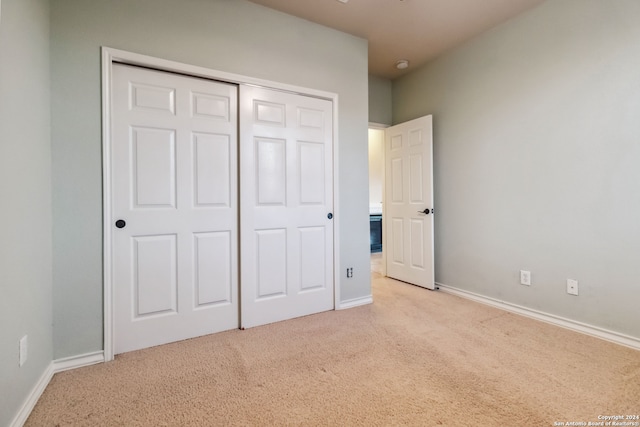 unfurnished bedroom featuring light colored carpet and a closet