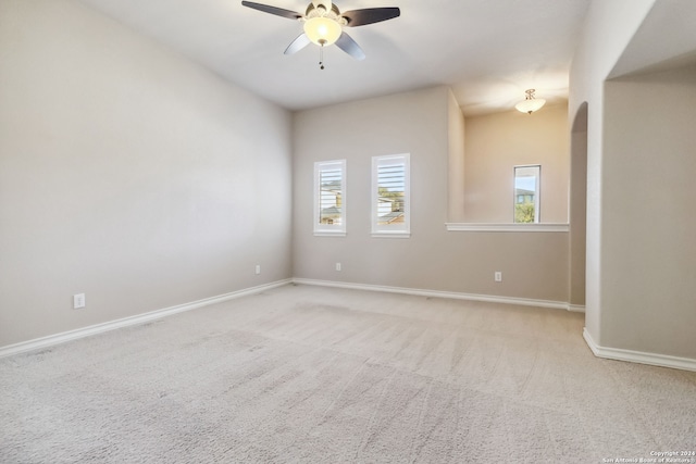 carpeted spare room featuring a wealth of natural light and ceiling fan