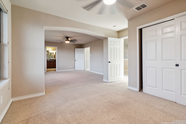 interior space with connected bathroom, a closet, light colored carpet, and ceiling fan