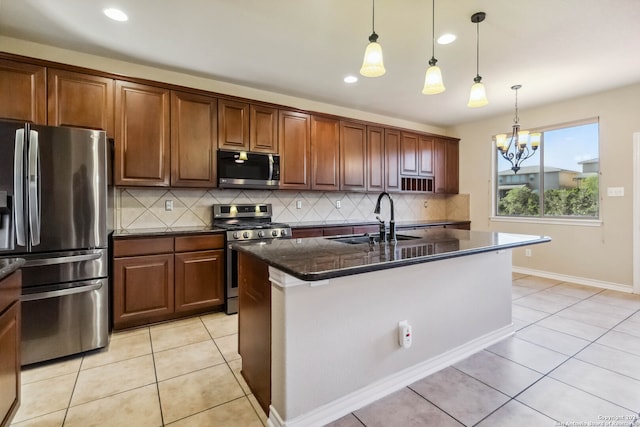 kitchen featuring sink, appliances with stainless steel finishes, decorative light fixtures, an island with sink, and decorative backsplash