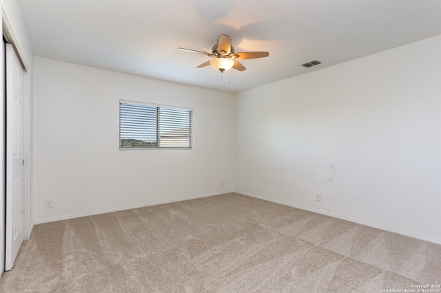 spare room with ceiling fan and light colored carpet