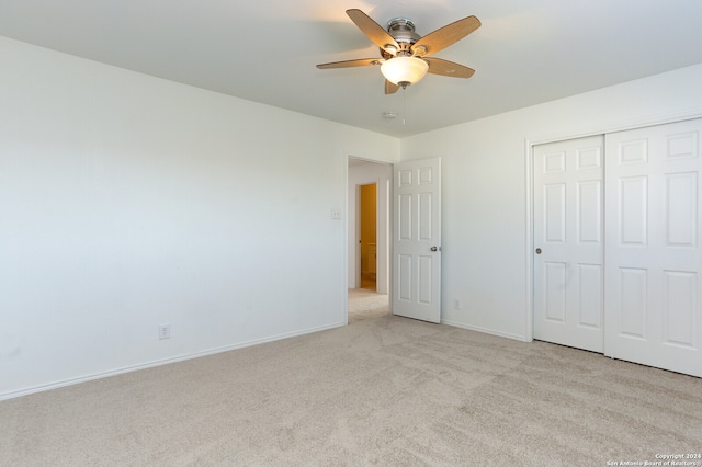 unfurnished bedroom featuring ceiling fan, light carpet, and a closet