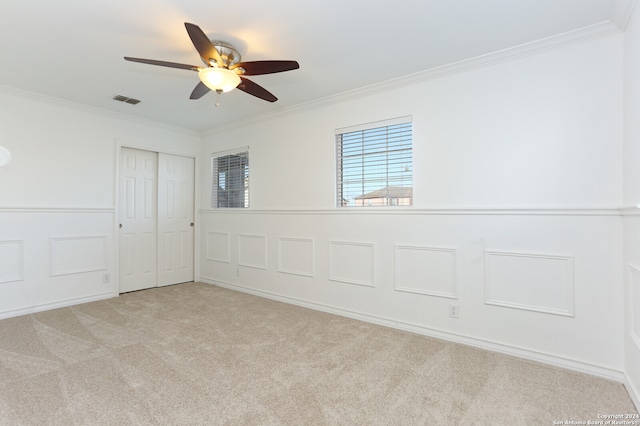 spare room with ceiling fan, light carpet, and crown molding