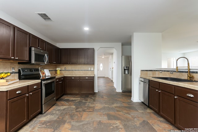 kitchen featuring dark brown cabinetry, appliances with stainless steel finishes, sink, and tasteful backsplash