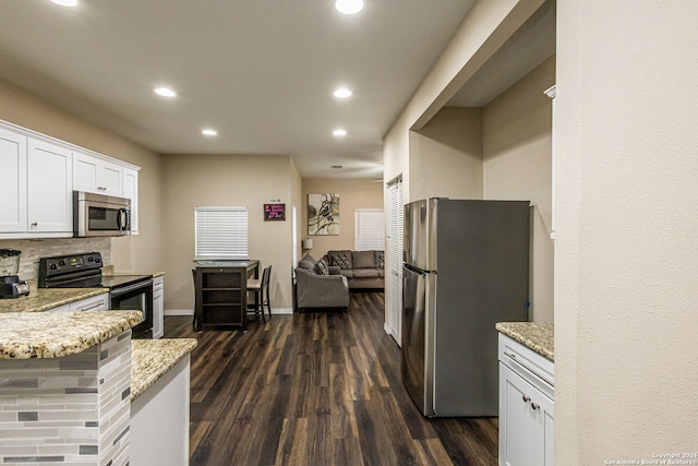 kitchen featuring dark wood-type flooring, tasteful backsplash, light stone countertops, white cabinetry, and appliances with stainless steel finishes