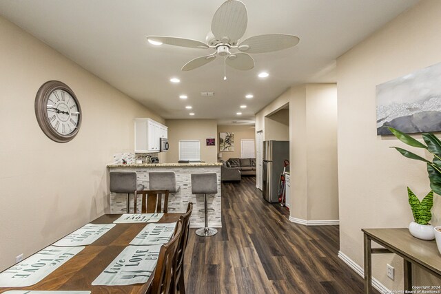 kitchen with a breakfast bar, appliances with stainless steel finishes, ceiling fan, dark hardwood / wood-style floors, and white cabinets