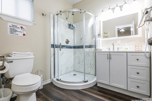 bathroom with toilet, hardwood / wood-style flooring, vanity, ceiling fan, and a shower with shower door