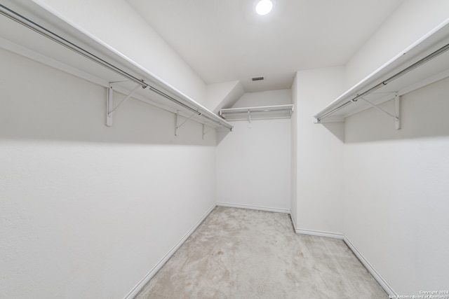 walk in closet with light colored carpet