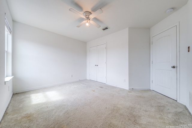 unfurnished bedroom featuring a closet, light carpet, and ceiling fan