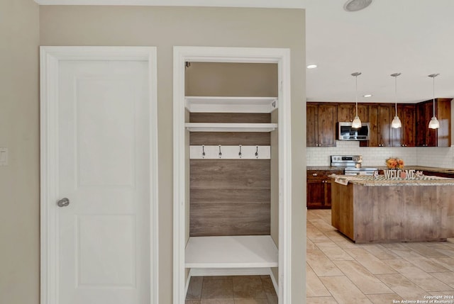 interior space featuring backsplash, decorative light fixtures, light stone counters, and stainless steel appliances