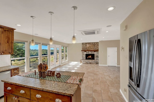 kitchen with dishwasher, hanging light fixtures, stainless steel fridge with ice dispenser, a kitchen island, and a fireplace