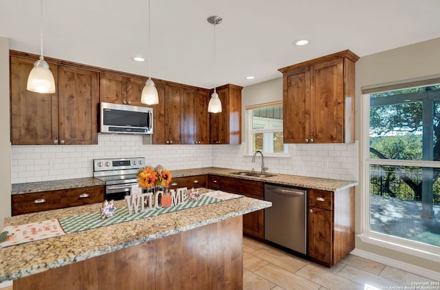 kitchen featuring pendant lighting, decorative backsplash, appliances with stainless steel finishes, and sink