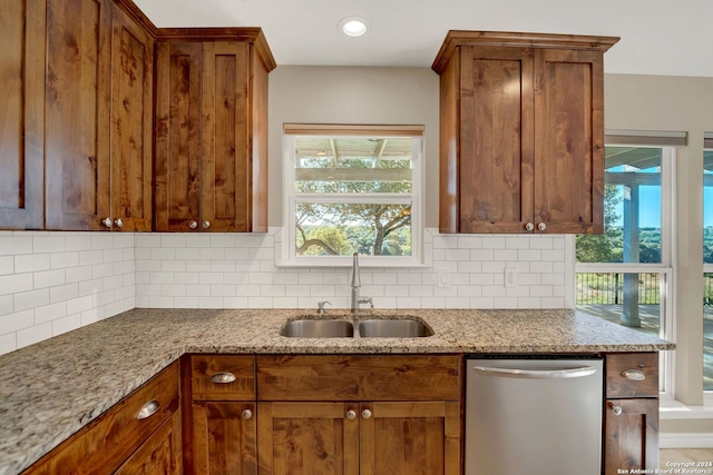 kitchen with dishwasher, a wealth of natural light, sink, and light stone counters