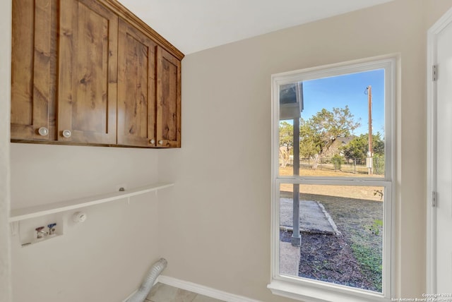 clothes washing area with electric dryer hookup and cabinets