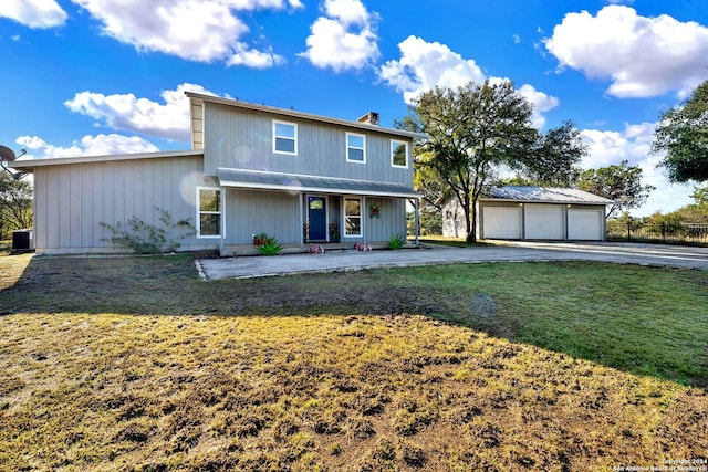 view of front of home with a garage, a front yard, and an outdoor structure