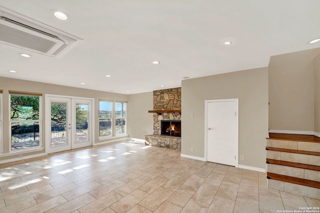 unfurnished living room with a stone fireplace and french doors