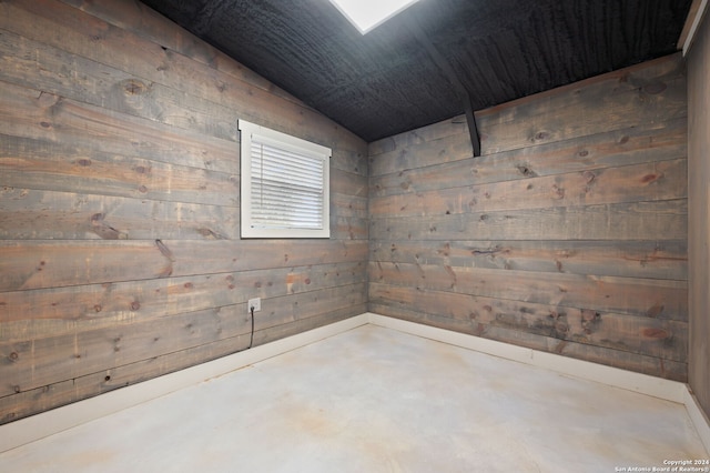 unfurnished room with wood walls and concrete floors