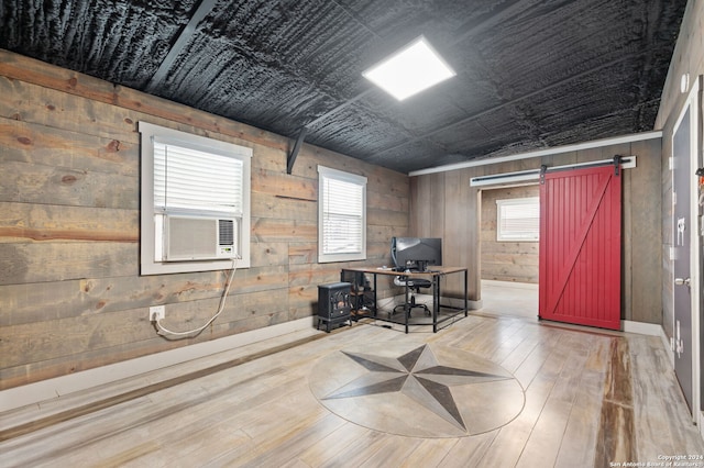 office featuring light wood-type flooring, wood walls, a barn door, and cooling unit