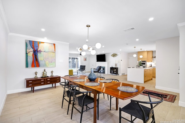 dining space featuring light wood-type flooring, a notable chandelier, and ornamental molding