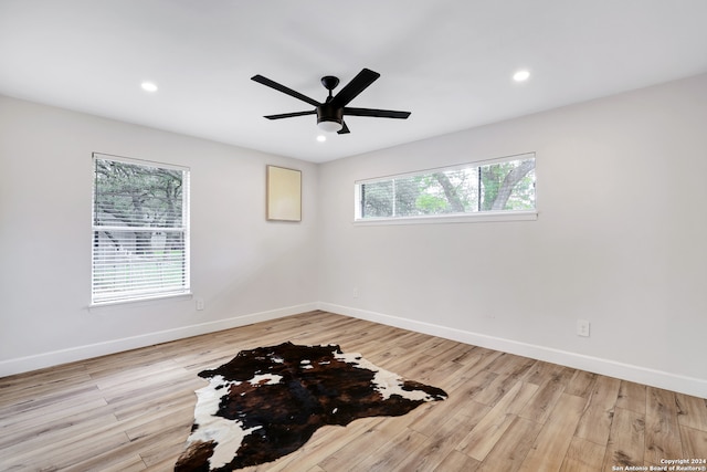 empty room featuring a wealth of natural light, ceiling fan, and light hardwood / wood-style floors