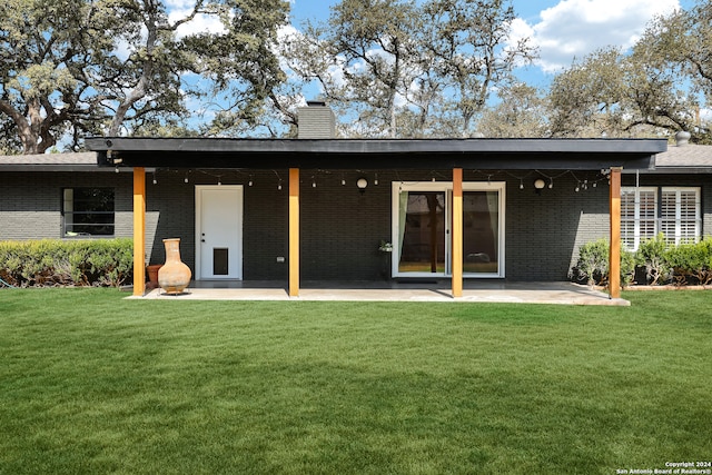 back of property with a lawn and a patio area